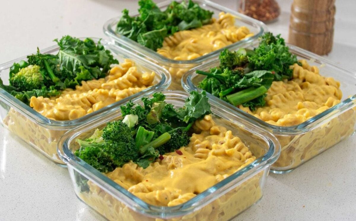 Four dishes of meal prepped high protein vegan mac and cheese with greens ontop, a high protein vegan dinner idea
