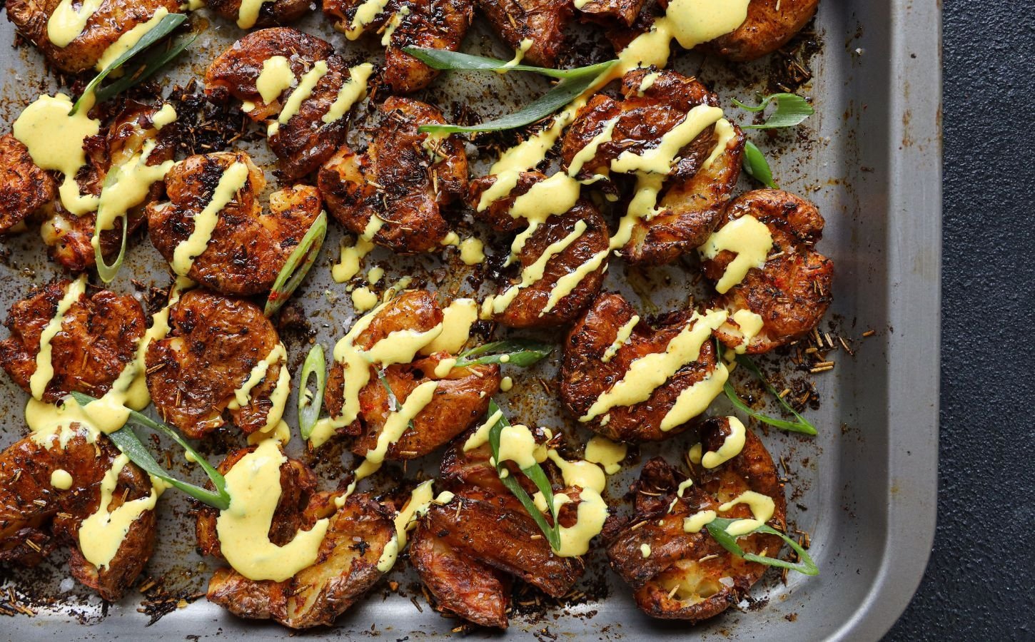 smashed new potatoes drizzled with a chili and turmeric vegan mayo dip, coated in seasonings and olive oil